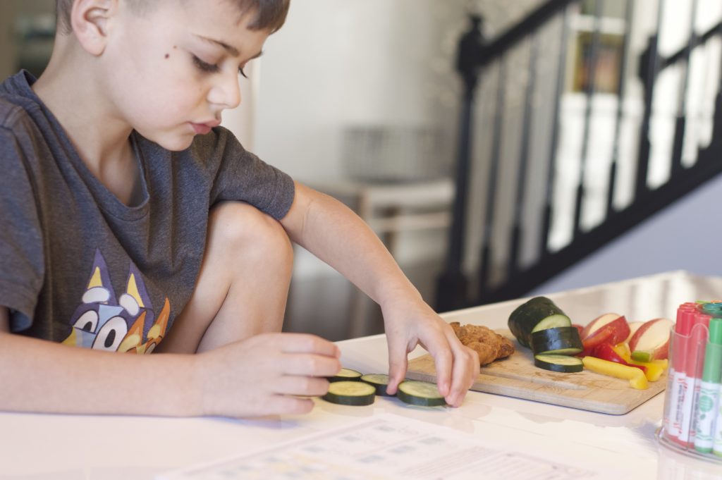 boy sitting at school table eating cucumbers