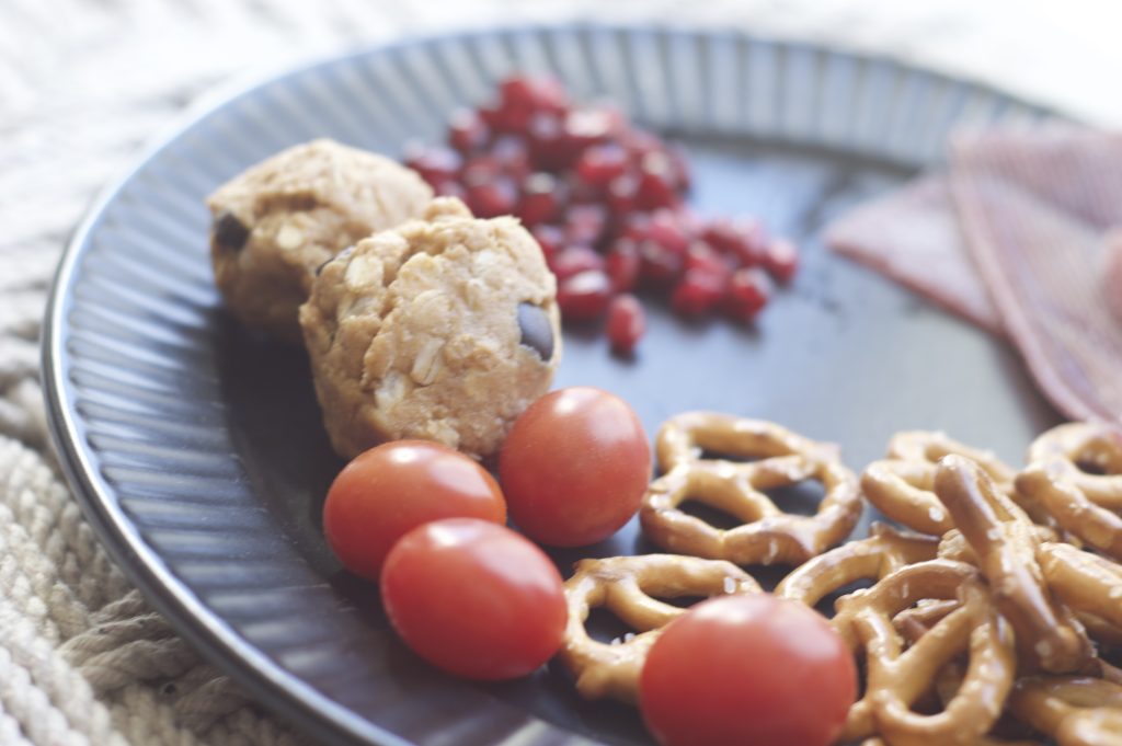 close up lunch of protein balls pomegranate seeds, tomatoes, pretzels to make healthy eating fun for kids