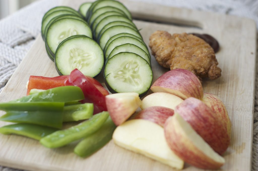 close up lunch with cucumbers, peppers, apples and chicken finger
